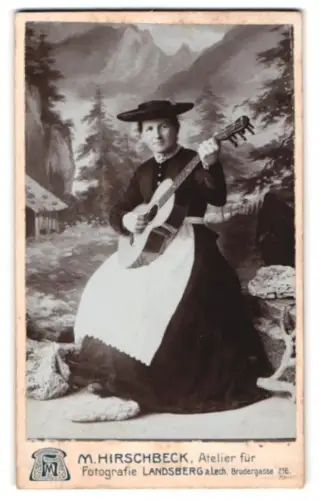 Fotografie M. Hirschbeck, Landsberg am Lech, Brudergasse 216, Frau in deutscher Tracht mit Gitarre vor Bergkulisse