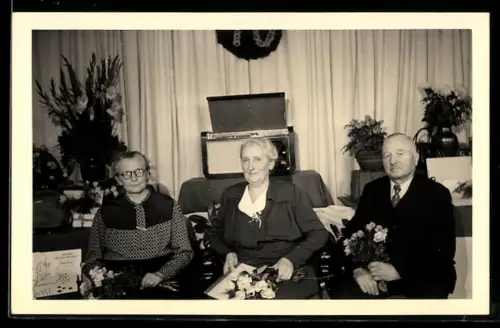 Foto-AK Zwei alte Damen und ein Herr sitzen vor einem Radio im Wohnzimmer