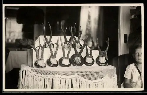 Foto-AK Junges Kind neben Rehgeweih-Trophäen