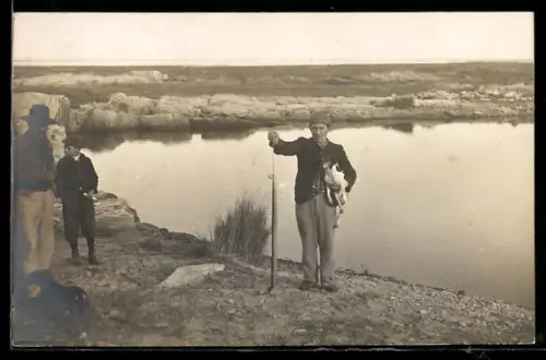 Foto-AK Jäger mit Jagdhund auf dem Arm vor einem See