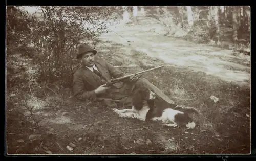 Foto-AK Jäger mit Gewehr und Jagdhund liegt im Gras