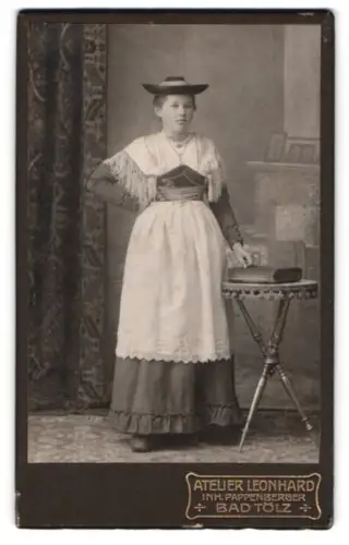 Fotografie Leonhard, Bad Tölz, Frau in deutscher Tracht neben einem Tisch stehend