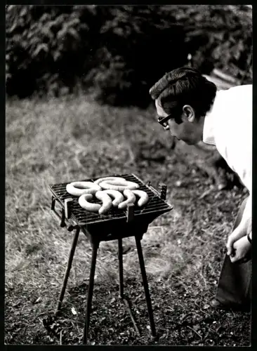 Fotografie Mann pustet auf Würstchen auf seinem Grill, Anblasen