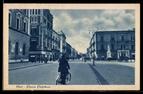 AK Bari, Piazza Prefettura con ciclista e statue in una giornata nuvolosa