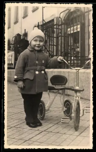 Foto-AK Kleinkind mit Mütze und einem Dreirad
