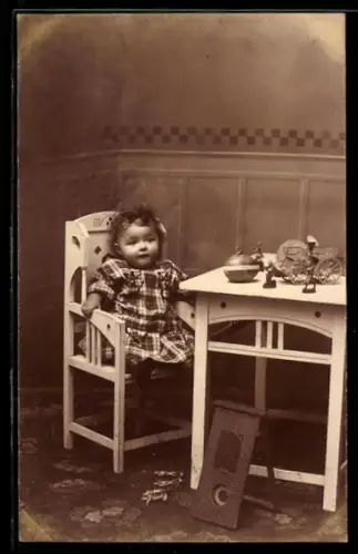 Foto-AK Kleinkind in einem Stuhl mit einem Tisch voller Spielzeug und Zinnsoldaten auf dem Boden