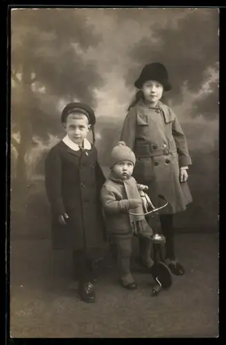 Foto-AK Drei Kinder mit einem Dreirad und einem Pferdespielzeug
