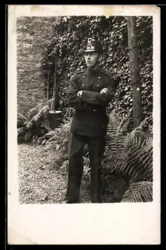 Foto-AK Schweizer Soldat in Uniform mit verschränkten Armen neben einem Baum