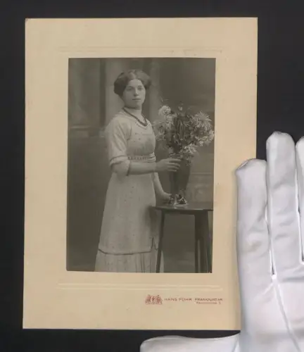 Fotografie Hans Fohr, Frankfurt a. M., Kaiserstrasse 3, Dame im gepunkteten Kleid steht neben einer Blumenvase