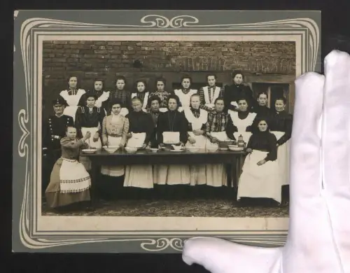 Fotografie Gruppenportrait mit Dienstmädchen mit Schürzen an einem gedeckten Tisch