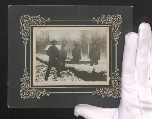 Fotografie Gruppenportrait von Holzfällern mit Säge an einem verschneiten Baum