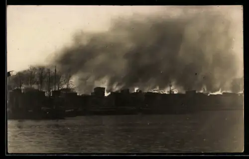 Foto-AK Lübeck, Grossbrand am 2.11.1913, Dunkler Rauch über dem Feuer vom Wasser aus gesehen