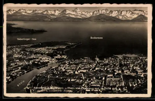 AK Konstanz /Bodensee, Ortsansicht mit Rhein, Überlinger See, Schweizer Alpen, Fliegeraufnahme