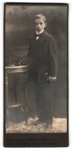 Fotografie J. Fuchs & Co, Charlottenburg, Wilmersdorferstr. 57, Junge in Anzug mit Buch