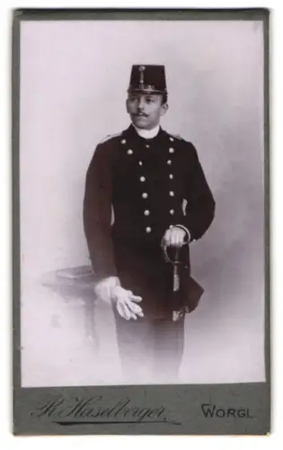 Fotografie Raim. Haselberger, Wörgl, Bahnhofstrasse 171, k.u.k Offizier im Uniformrock mit Kappe und Säbel