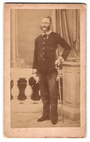 Fotografie unbekannter Fotograf und Ort, k.u.k. Offizier in Uniform mit Kappe und Säbel