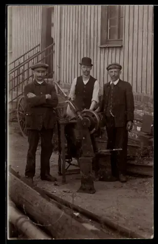 Foto-AK Drei Handwerker mit Werkzeugmaschine vor der Werkstatt