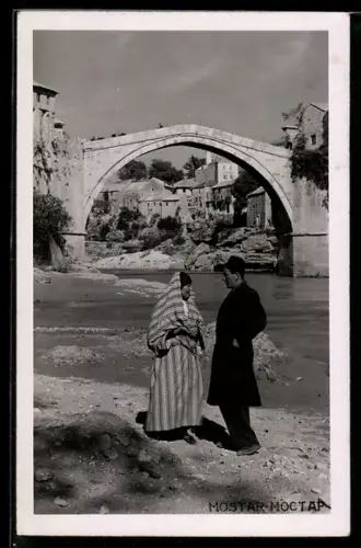 AK Mostar, Alte Brücke mit zwei Einheimischen am Flussufer