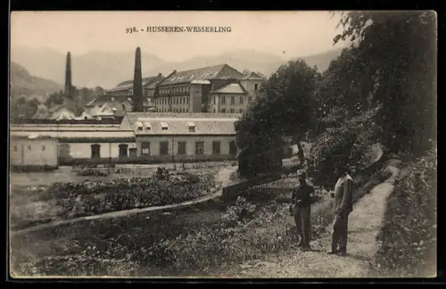 AK Husseren-Wesserling, Fabrik mit Schornsteinen und zwei Spaziergängern