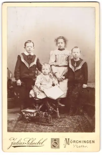 Fotografie Julius Scheubel, Mörchingen i. Lothr., Porträt von vier Kindern mit Spielzeug im Februar 1895