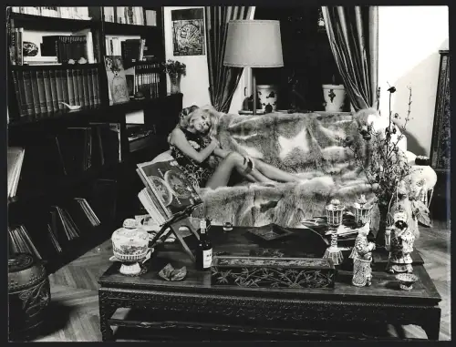 Fotografie Schauspielerin Mireille Darc zeigt ihre Beine auf einer Couch mit Pelz