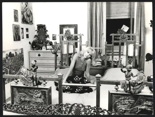 Fotografie Schauspielerin Mireille Darc sitzt in legerer Kleidung auf einem Bett