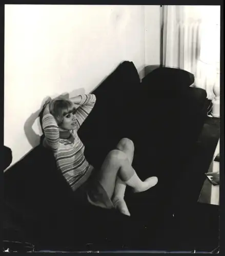 Fotografie Schauspielerin Mireille Darc sitzt im Rock auf einem Sofa