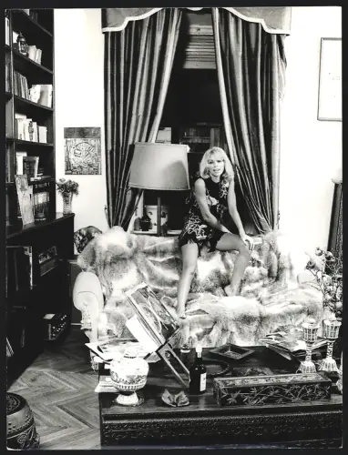 Fotografie Schauspielerin Mireille Darc sitzt im Kleid und mit nackten Beinen auf einer Sofalehne