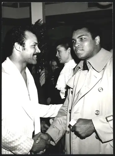 Fotografie Boxer Muhammad Ali im Trenchcoat schüttelt die Hand eines Mannes, Grossformat 19 x 25cm