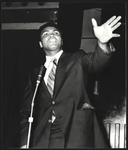 Fotografie Boxer Muhammad Ali im Anzug steht an einem Mikrofon