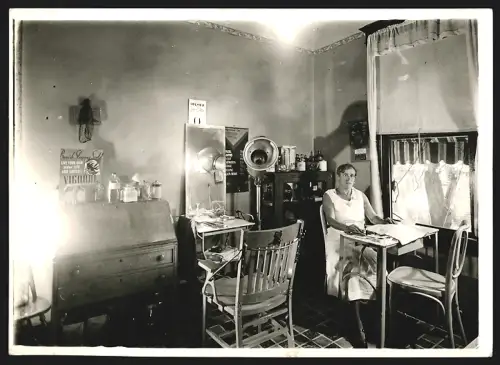 Fotografie unbekannter Fotograf und Ort, Friseuse in ihrem Geschäft 1933, Preisliste an der Wand