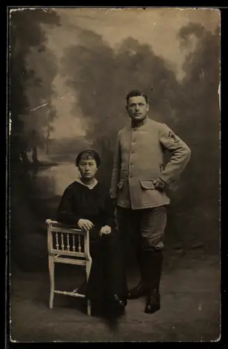 Foto-AK Soldat und eine Frau vor Studiokulisse mit See