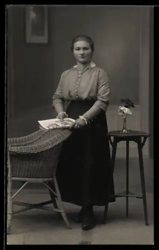 Foto-AK Elegante Frau mit Zeitung vor Studiokulisse eines Wohnraumes
