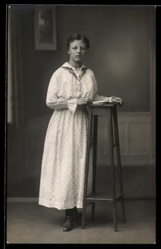 Foto-AK Elegante junge Frau mit Buch vor Studiokulisse