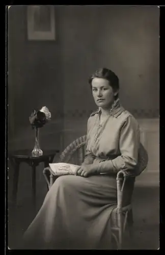 Foto-AK Sitzende junge Dame vor ruhiger Studiokulisse