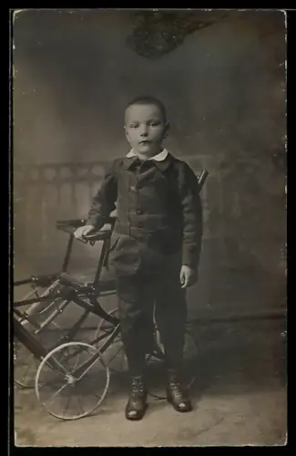 Foto-AK Kleiner Junge mit Wagen vor einer Studiokulisse