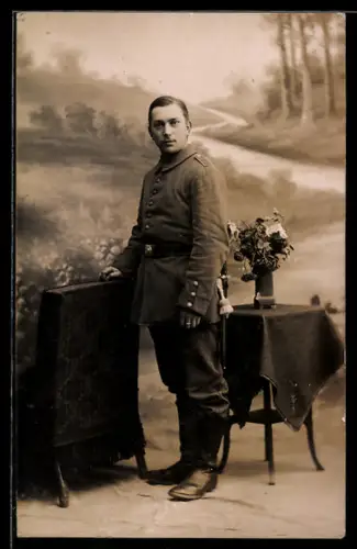 Foto-AK Soldat in Uniform vor Studiokulisse eines Feldweges