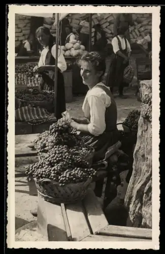 Foto-AK Junge Frau mit Körben voller Weintrauben auf einem Markt