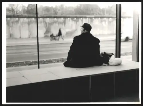 Fotografie Ansicht Berlin, Mann sitzt auf einer Bank in der Bernauerstrasse 4 mit Blick auf die Mauer, 18 x 25cm