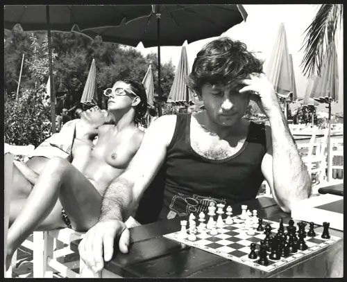 Fotografie Roman Polanski beim Schachspiel, hinter ihm sonnt sich eine halbnackte Frau, Grossformat 21 x 26cm