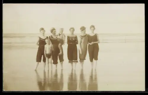 Foto-AK Damengruppe in Badeanzügen und Knabe in Badehose im flachen Wasser am Meer