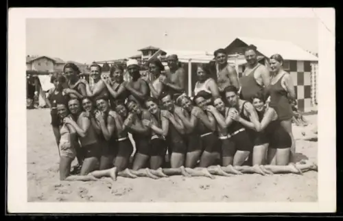 Foto-AK Fröhliche Gruppe in Badeanzügen am Strand, Gebäude im Hintergrund