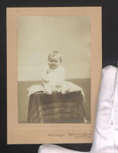 Fotografie Adolf Ellinger, Frankfurt a. M., De Neufvillestr. 34, Grinsendes Kleinkind auf einem Fell sitzend