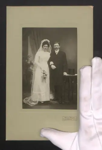 Fotografie Alb. Fick, Cadenberge /U. E., Elegantes Hochzeitspaar mit Schleier, Blumenstrauss und Zylinder, 25 x 16cm