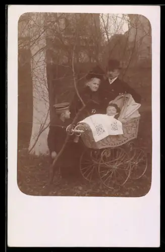 Foto-AK Grosseltern mit Knabe u. Kleinkind im Kinderwagen in einem Park