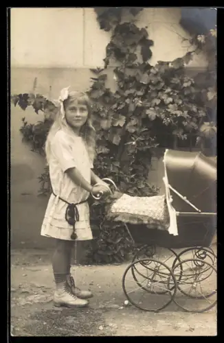 Foto-AK Kleines Mädchen mit Puppe im Kinderwagen vor einer Hauswand