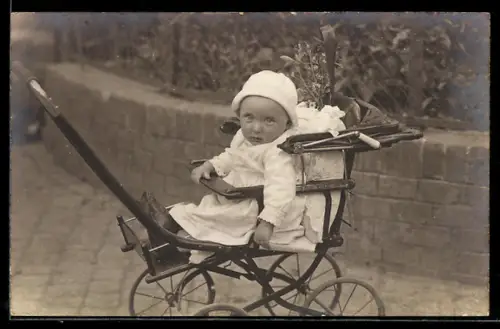 Foto-AK Kleinkind mit Hut im Kinderwagen neben einem Mäuerchen