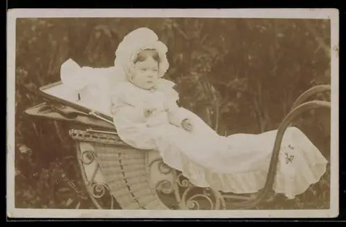 Foto-AK Kleines Mädchen mit Haube im verschnörkelten Korb-Kinderwagen