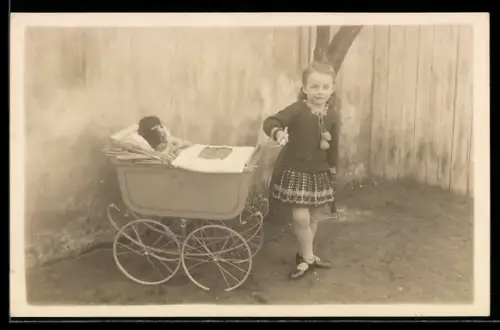 Foto-AK Kleines Mädchen in Lackschuhen mit Puppe im Kinderwagen in einem Hof