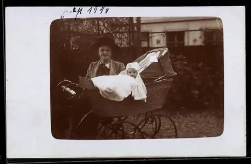 Foto-AK Lächelnde junge Dame und Kleinkind im Kinderwagen in einem Garten, 1914